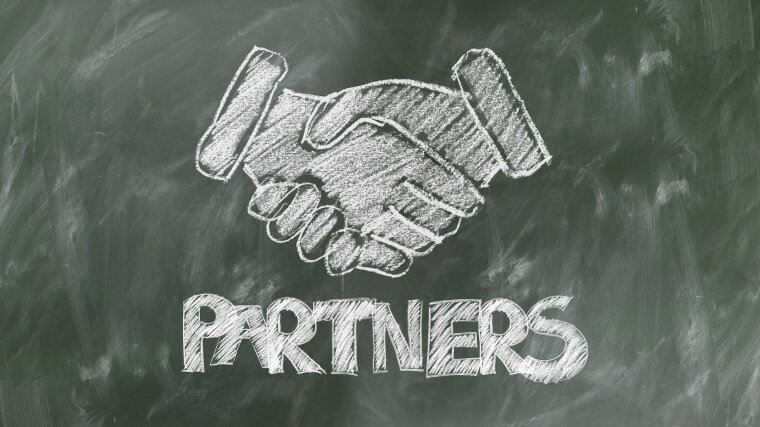 Shaking hands painted with chalk on a blackboard.