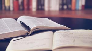 Buch und Notizheft vor Büchern