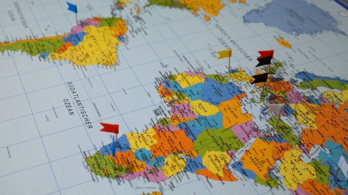 Karte mit Afrika, Südamerika sowie Europa mit eingesteckten Fahnen